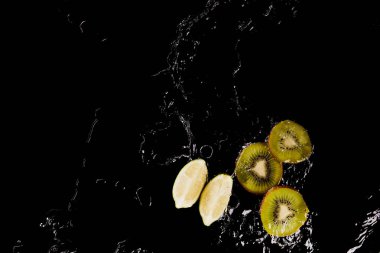 top view of cut lemon and kiwi in clear water puddle isolated on black clipart