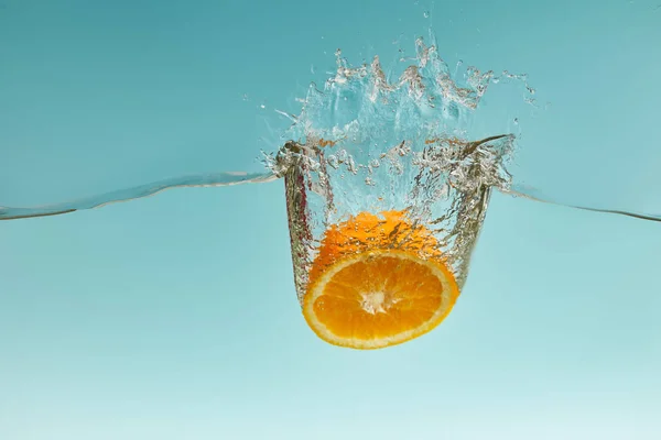 Medio Naranja Madura Cayendo Agua Con Salpicadura Sobre Fondo Azul — Foto de Stock