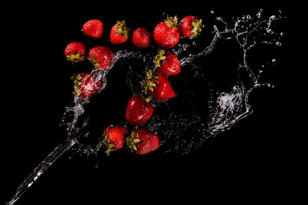 сверху вид спелой клубники с водяным брызгом, изолированным на черном
