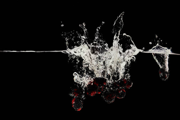 fresh ripe berries falling in water with splash isolated on black