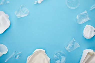 top view of disposable plastic cups, forks, spoons and containers on blue background with copy space clipart