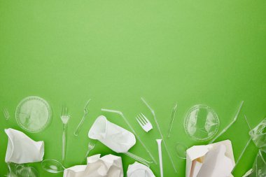 kopya alanı ile yeşil arka plan üzerinde tek kullanımlık plastik bardak, çatal, kaşık ve karton kaplar üst görünümü