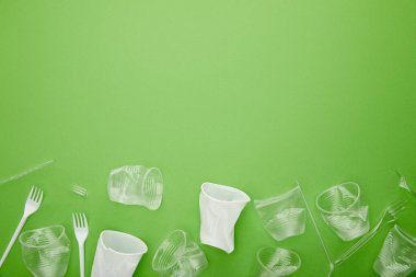 kopya alanı ile yeşil arka plan üzerinde buruşuk plastik bardak ve çatal üst görünümü