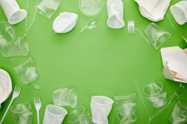 kopya alanı ile yeşil arka plan üzerinde buruşuk plastik bardak, çatal ve karton konteyner üst görünümü 
