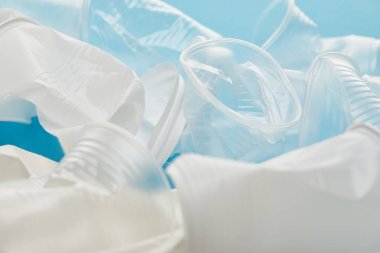mavi arka plan üzerinde buruşturulmuş beyaz ve şeffaf plastik bardak
