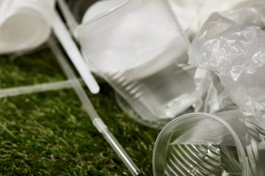 çim üzerinde buruşuk plastik bardak ve torbaların yakın görünümü