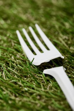 yeşil çim kırık tek kullanımlık plastik çatal yakından görünümü