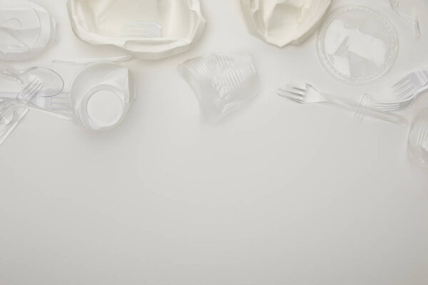 top view of crumpled plastic cups, plates, forks and spoons on white background with copy space