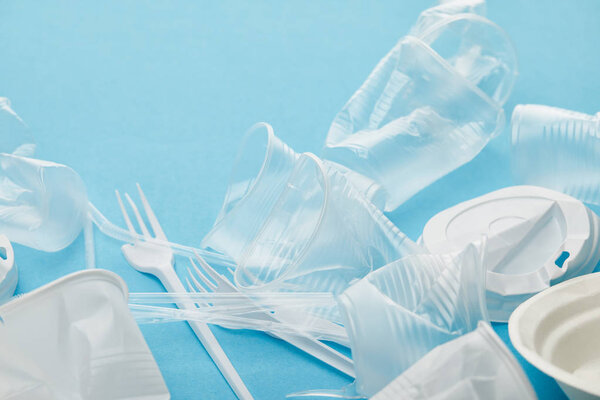 crumpled plastic cups and forks on blue background