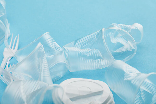 crumpled transparent plastic cups on blue background