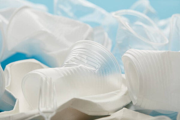 close up view of stack of transparent and white plastic cups on blue background