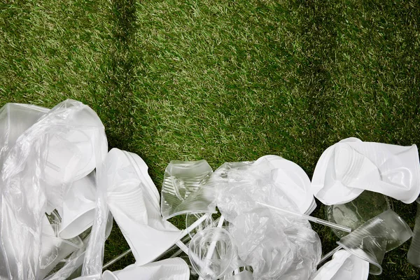 コピースペース付きの草の上にくしゃくしゃのプラスチックや段ボールのゴミのトップビュー — ストック写真