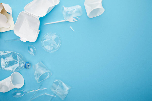 top view of plastic and cardboard rubbish on blue background with copy space