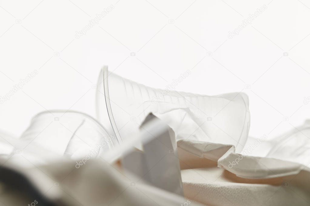 close up view of crumpled transparent plastic cups in pile of rubbish on white background