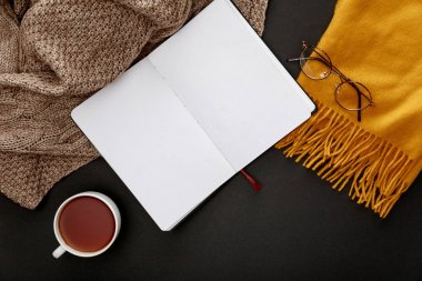 siyah arka plan üzerinde uyarmak eşarplar ve boş dizüstü yakın kupa çay üst görünümü