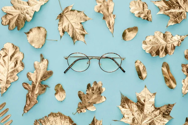 青い背景に秋の黄金の葉と眼鏡のトップビュー — ストック写真