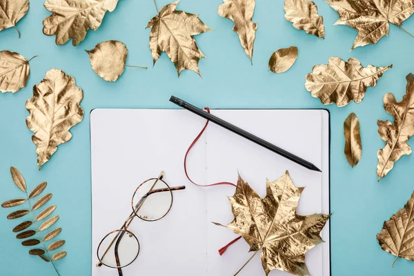 Top View Autumnal Golden Leaves Blank Notebook Glasses Blue Background — Stock Photo, Image