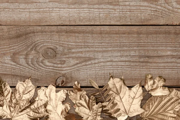 木製のテクスチャの背景に金色の葉のトップビュー — ストック写真