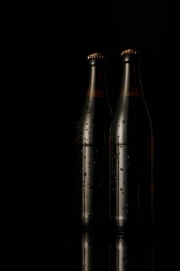 glass bottles of beer with drops isolated on black clipart