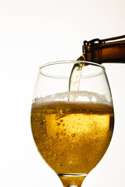 low angle view of beer pouring from bottle into glass isolated on white