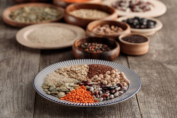 деревянные и керамические плиты с бобовыми и зерновыми на коричневом столе
