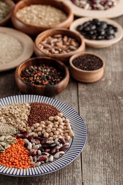 テーブルの上に豆類と穀物が付いている木製および陶磁器の版 — ストック写真