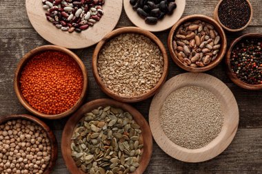 ahşap yüzeyde ham yulaf ezmesi, kırmızı mercimek, çeşitli fasulye, Kinoa, nohut, biber ve kabak çekirdeği ile kase üst görünümü