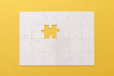 top view of white jigsaw puzzle with lost piece on yellow background clipart