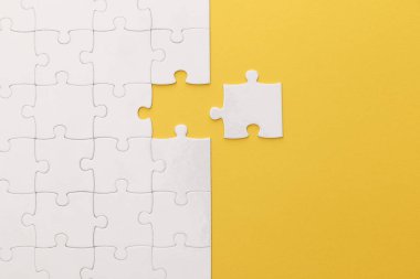top view of white jigsaw puzzle on yellow background clipart