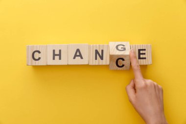 cropped view of woman switching wooden cube from word change to chance on yellow background clipart