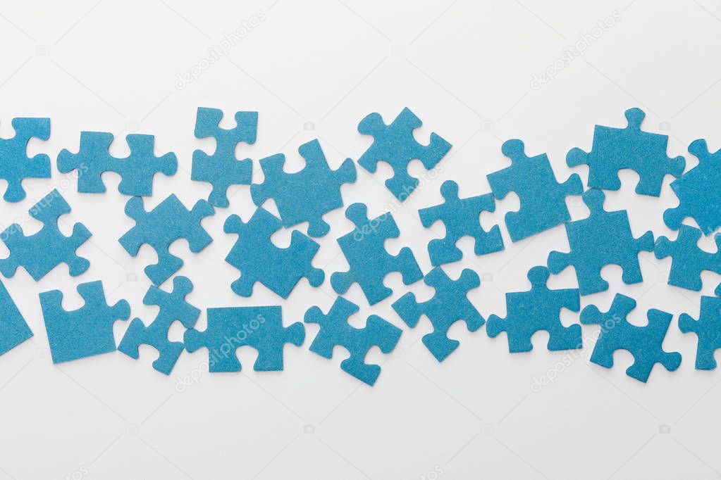 top view of scattered pieces of blue jigsaw puzzle on white background