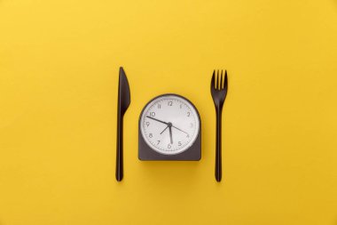 sarı arka plan üzerinde bıçak ve çatal arasındaki saatin üst görünümü