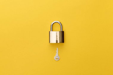 top view of padlock and key on yellow background clipart