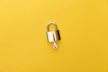 top view of key in padlock on yellow background clipart