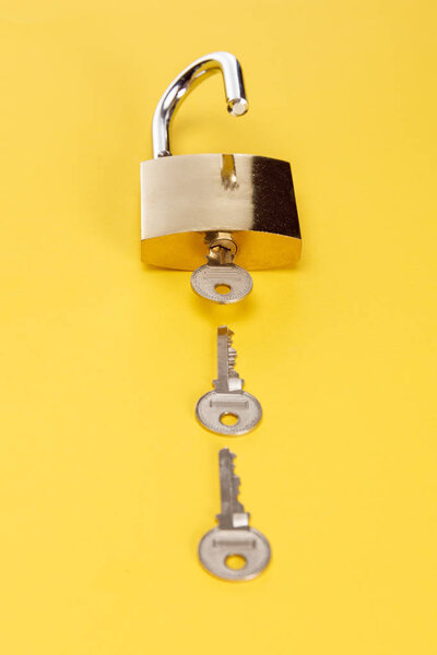 metal padlock with keys on yellow background