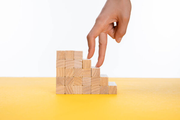 cropped view of woman stepping with fingers on wooden steps on yellow surface isolated on white