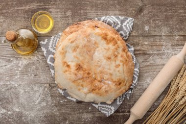 buğday sivri, oklava ve ahşap masada zeytinyağı şişesi yakın desen ile havlu üzerinde lavaş ekmek üst görünümü