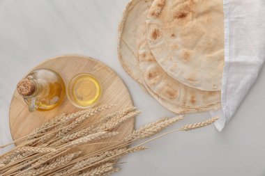mermer yüzeyinde sivri ve yağ ile kesme tahtası yakınında beyaz havlu ile düz lavaş ekmek üst görünümü