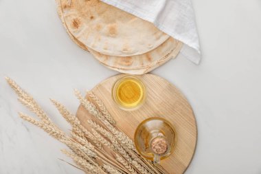 mermer yüzeyinde sivri ve yağ ile kesme tahtası yakınında beyaz havlu ile kaplı lavaş ekmek üst görünümü