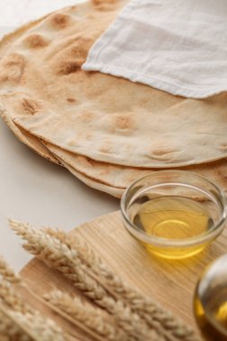 lavash bread covered with white towel near cutting board with spikes and oil clipart