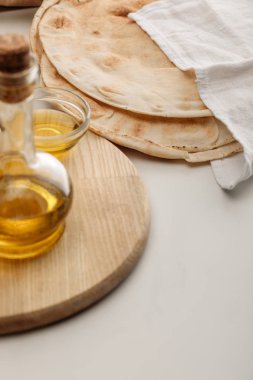 lavaş ekmek beyaz yüzeyüzerinde yağ ile kesme tahtası yakınında havlu ile kaplı
