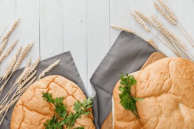 beyaz ahşap yüzeyüzerinde sivri yakın gri havlu üzerinde maydanoz ile lavaş ekmek üst görünümü