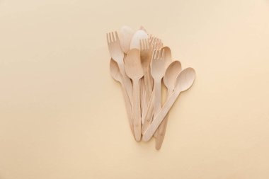 top view of natural wooden spoons and forks on beige background clipart