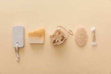 bej arka plan üzerinde pamuklu bez, loofah ve pomza taşı yakınında doğal sabun üst görünümü