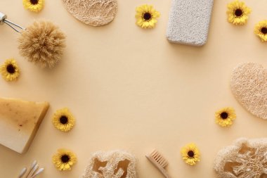 loofah üst görünümü, pamuklu bezler, vücut fırçası, diş fırçası ve çiçek ve kopya alanı ile bej arka plan üzerinde sabun parçası