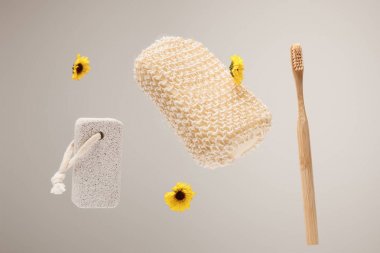 diş fırçası, pomza taşı, banyo süngeri ve gri izole sarı çiçekler