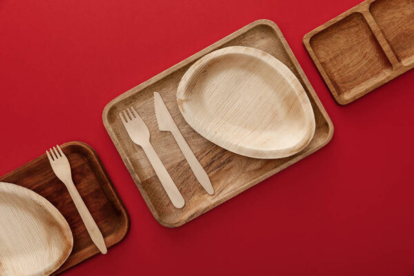 top view of rectangular wooden dishes with plates and cutlery on red background