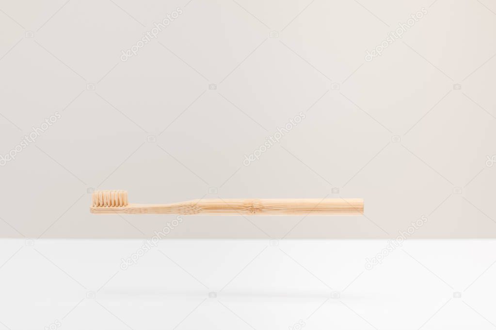 wooden toothbrush above white surface isolated on gray