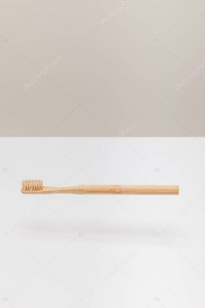 natural wooden toothbrush above white surface isolated on gray