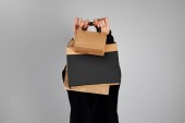 nő homályos arc gazdaság papír bevásárló táskák elszigetelt szürke, fekete péntek koncepció